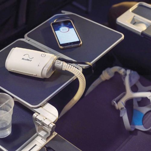 a travel CPAP on a tray table onboard an airplane